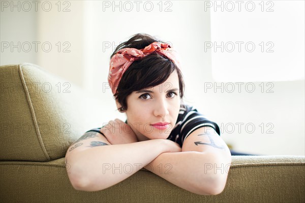 Young woman sitting on sofa. Photo : Jessica Peterson