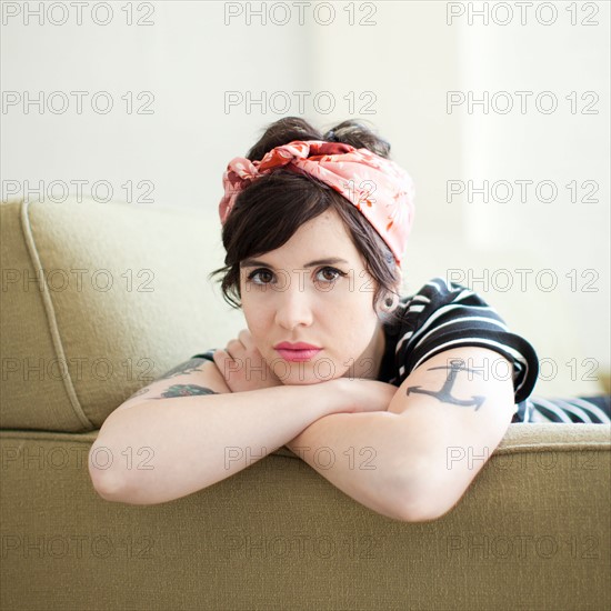 Young woman sitting on sofa. Photo : Jessica Peterson
