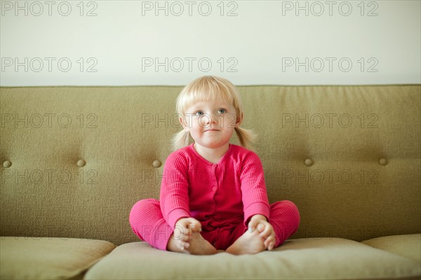 Portrait of baby girl (18-23 months) sitting on sofa. Photo : Jessica Peterson