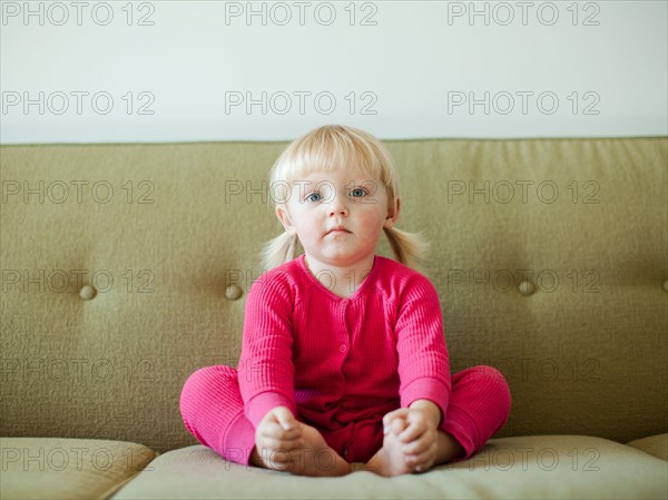 Portrait of baby girl (18-23 months) sitting on sofa. Photo : Jessica Peterson