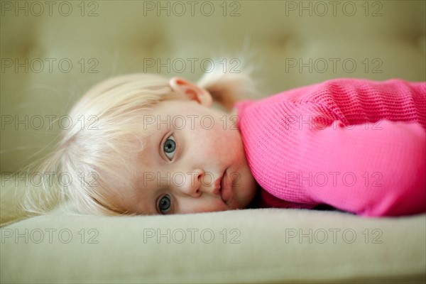 Portrait of baby girl (18-23 months) resting on sofa. Photo : Jessica Peterson