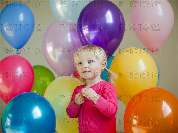 Portrait of baby girl (18-23 months) wit colorful balloons. Photo : Jessica Peterson