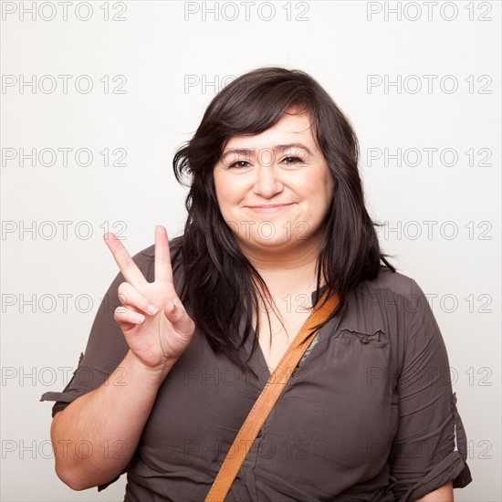 Studio Shot of young woman making Peace Sign . Photo : Jessica Peterson