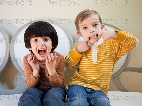 Studio Shot portrait of two boys (4-5, 6-7) sitting side by side. Photo : Jessica Peterson