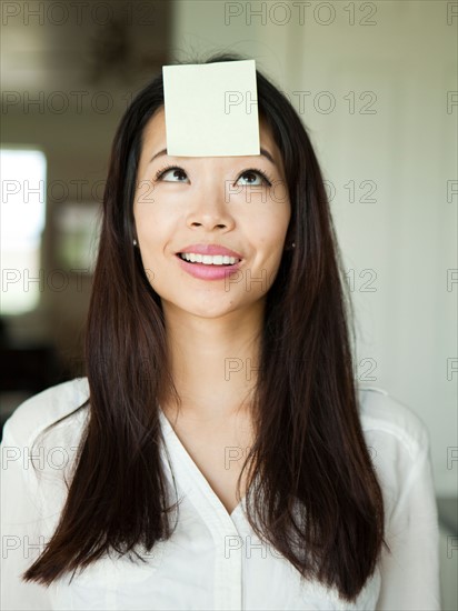 Portrait of young woman with adhesive note stuck to her forehead. Photo : Jessica Peterson