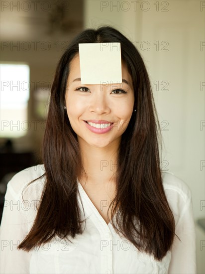 Portrait of young woman with adhesive note stuck to her forehead. Photo : Jessica Peterson