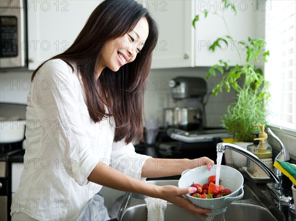 Portrait of young woman washing strawberries. Photo : Jessica Peterson