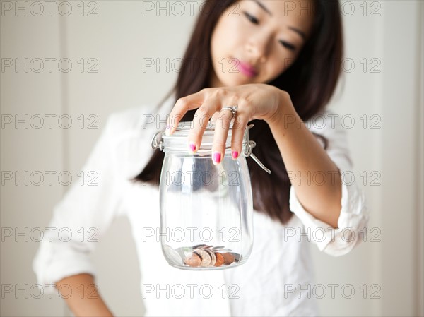 Young woman holding jar with coins inside. Photo : Jessica Peterson