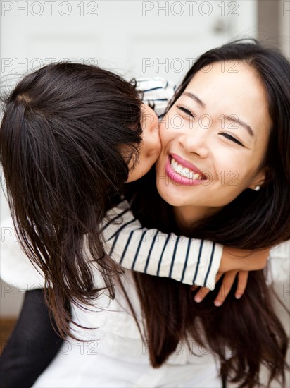 Smiling woman kissing by her daughter (4-5). Photo : Jessica Peterson