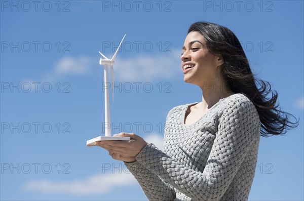 Young woman holding toy wind turbine.