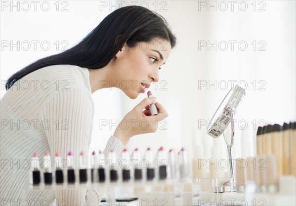 Young woman applying lipstick.