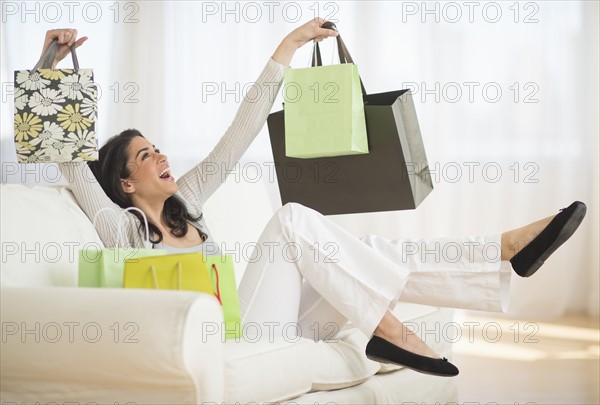 Young woman with shopping bags on sofa.