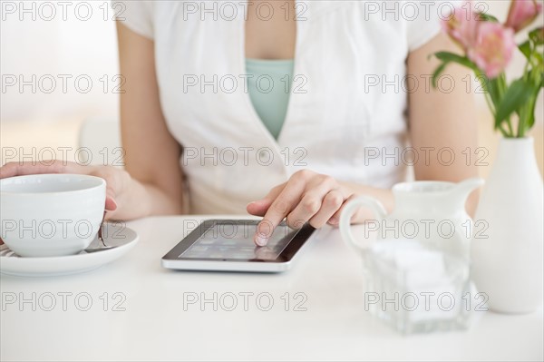 Midsection of young woman using tablet pc in restaurant.