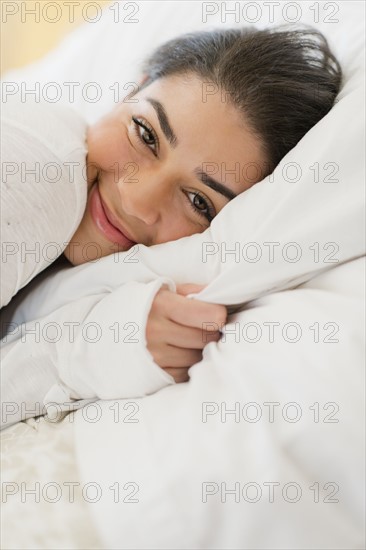 Portrait of young woman lying in bed.