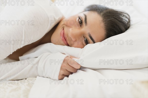 Portrait of young woman lying in bed.