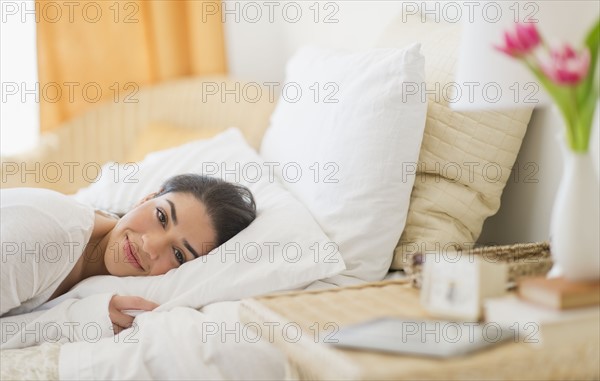 Portrait of young woman lying in bed.