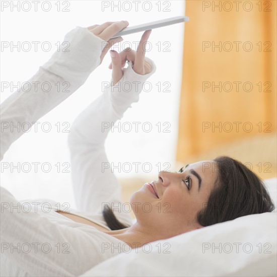 Young woman lying on bed using tablet pc.