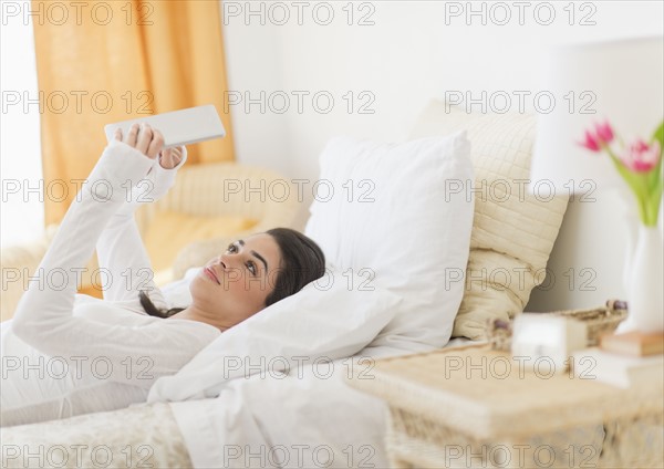 Young woman lying on bed using tablet pc.