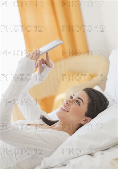 Young woman lying on bed using tablet pc.