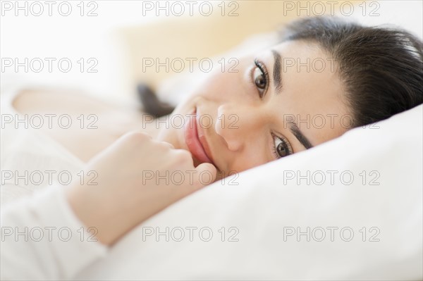 Portrait of young woman lying in bed.