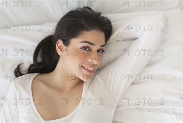 Portrait of young woman lying in bed.