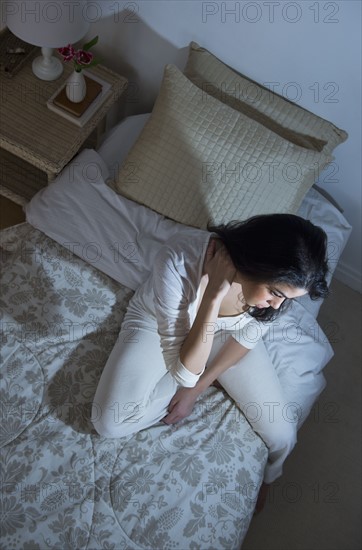 Young woman sitting on bed.