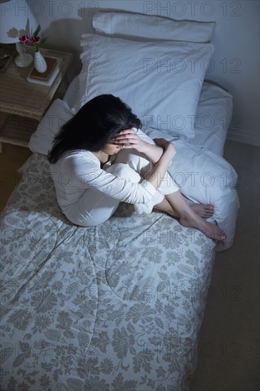 Young woman sitting on bed.