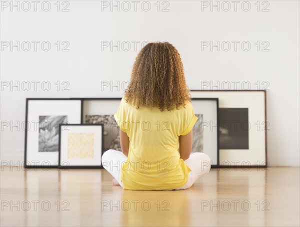 Woman sitting on floor looking at artworks.