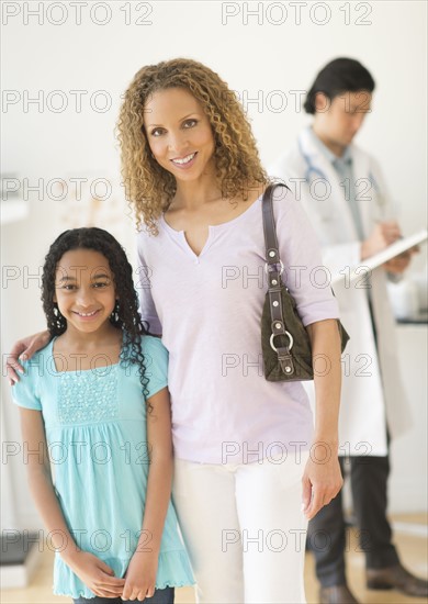 Portrait of mother with daughter (12-13) at doctor's office.