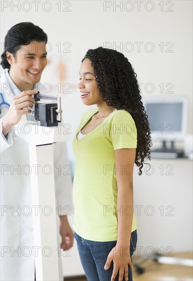 Doctor weighing female patient (10-11).