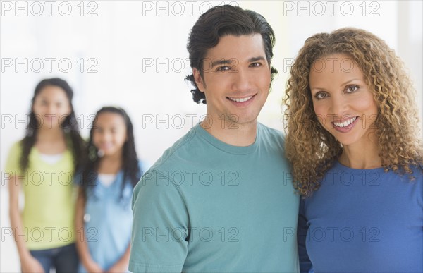 Portrait of parents with daughters (10-13) in background.