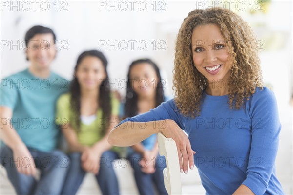 Portrait of woman with husband and daughters (10-13) in background.