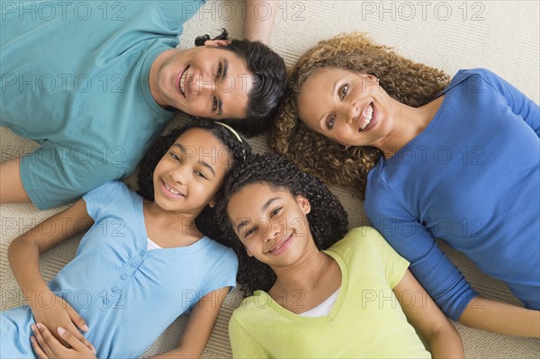 Portrait of parents with daughters (10-13) lying on floor.