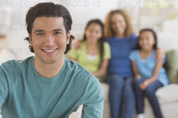 Portrait of man with wife and daughters (10-13) in background.