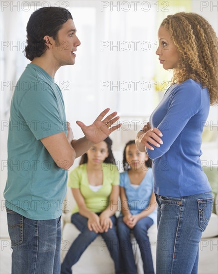 Parents quarreling, with daughters (10-13) in background.