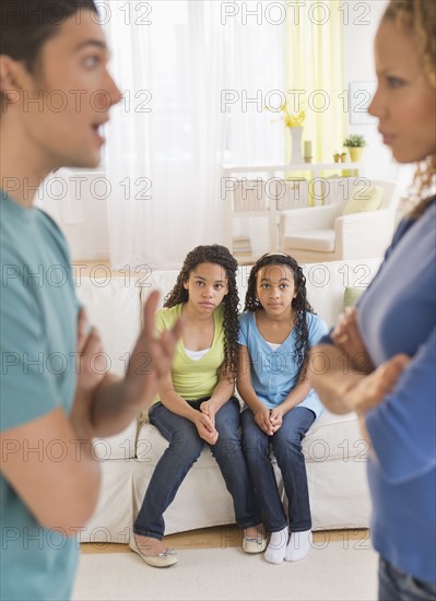 Parents quarreling, with daughters (10-13) in background.