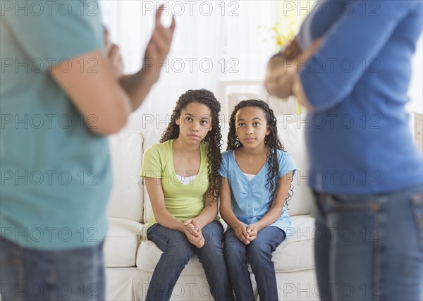 Parents quarreling, with daughters (10-13) in background.