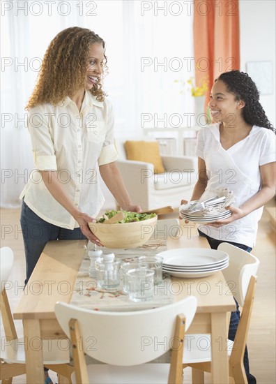 Mother with daughter (10-11) setting table.