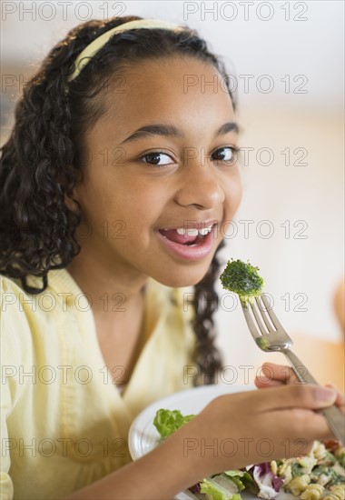 Portrait of girl (12-13) eating dinner.