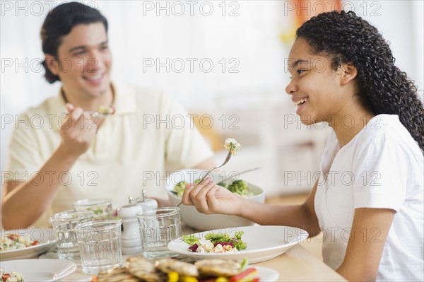 Father with daughter (10-11) eating dinner.