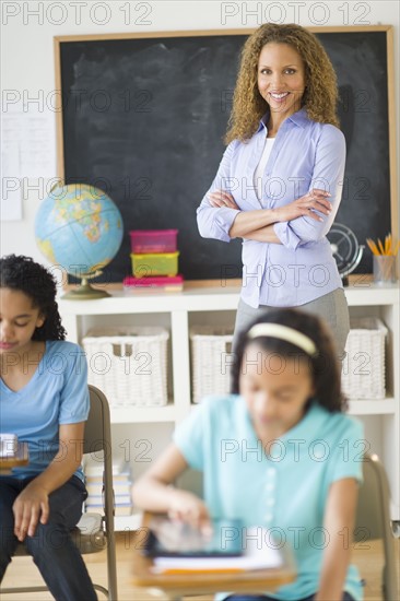 Portrait of female teacher in classroom with schoolgirls (10-13).