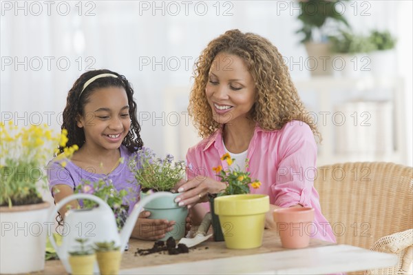 Mother with daughter (12-13) potting flowers.