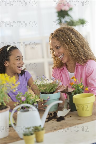 Mother with daughter (12-13) potting flowers.