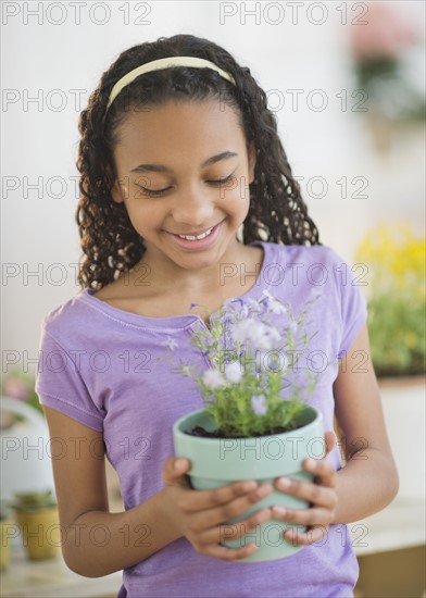 Girl (10-11) holding potted flower.