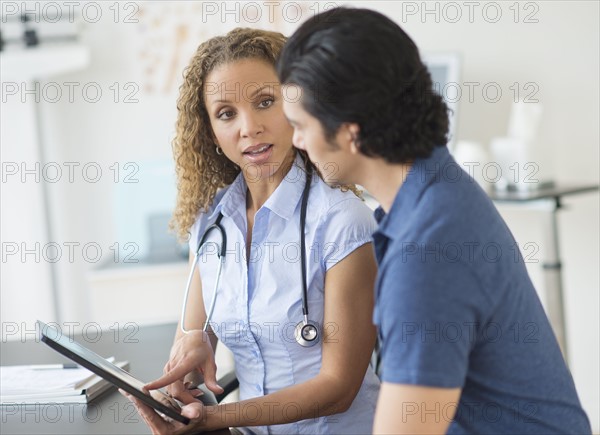 Doctor and patient talking in clinic using tablet pc.