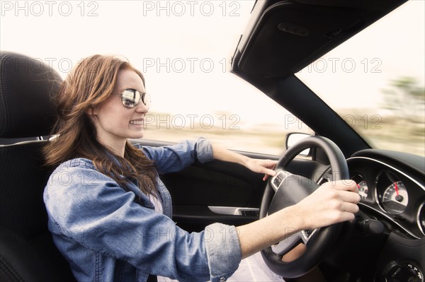 Young woman driving convertible.