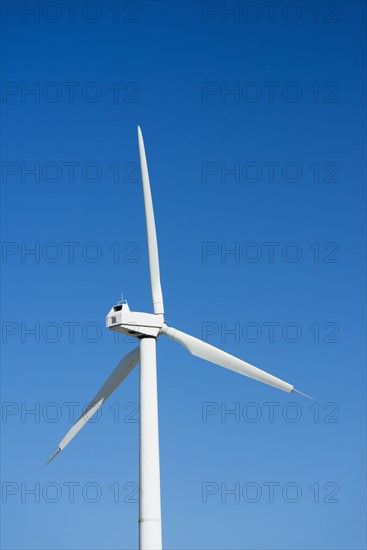 Wind turbine against blue sky.