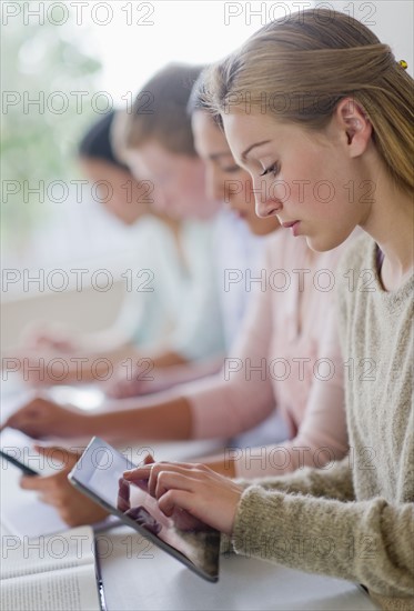 Students (14-19) using digital tablets in classroom.