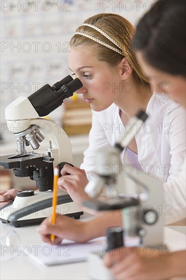 Students (16-19) in chemistry lab using microscope.