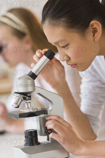 Students (14-17) in chemistry lab using microscope.